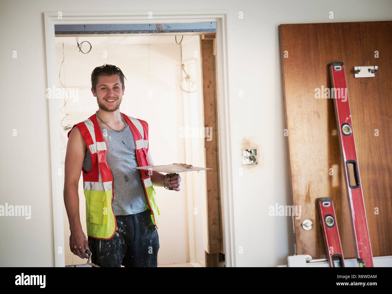 Portrait smiling construction worker plastering in house Stock Photo