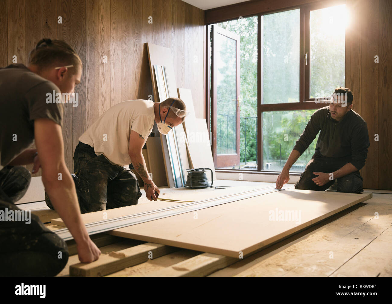 Construction workers measuring wood board Stock Photo