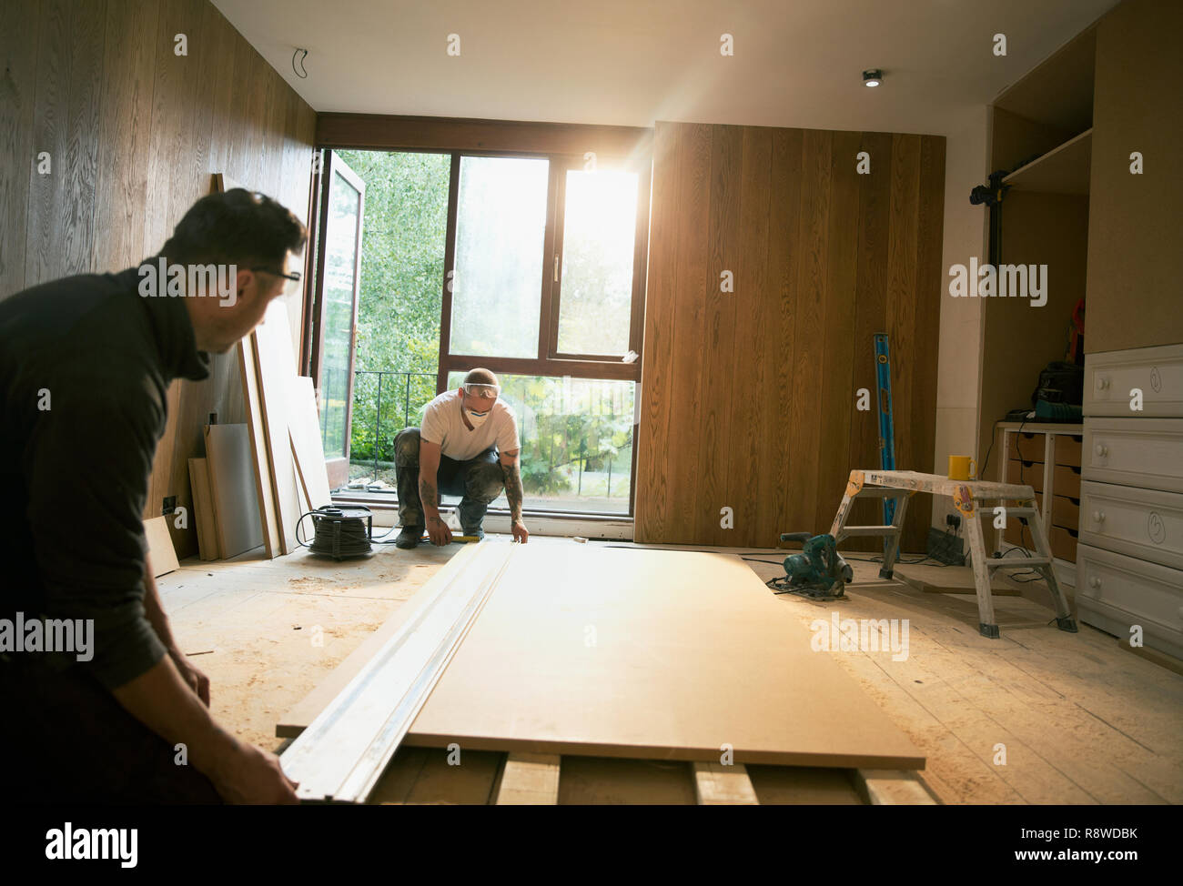 Construction workers measuring wood board in house Stock Photo