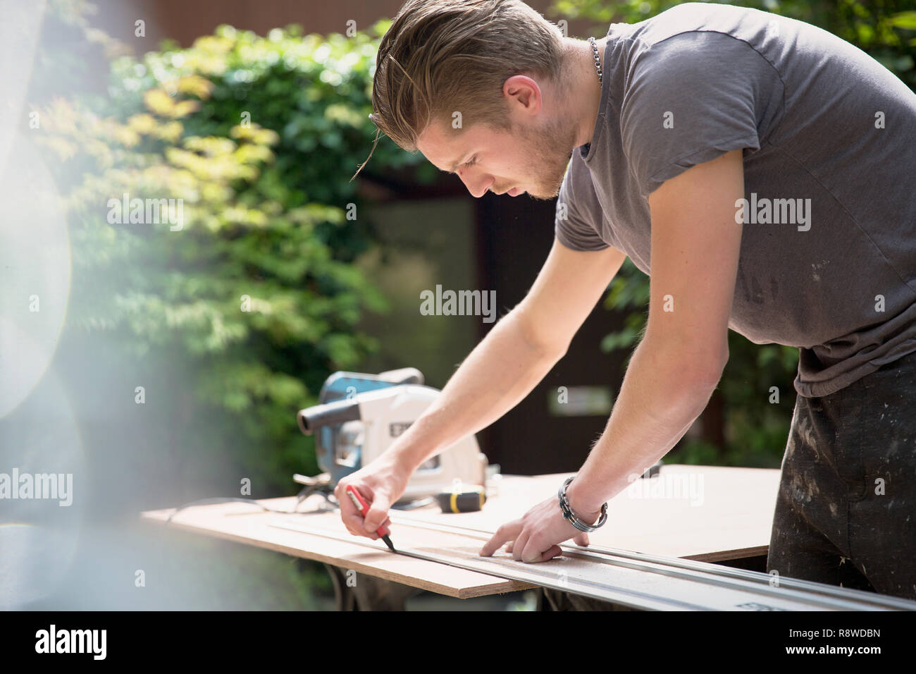 Construction worker measuring wood in driveway Stock Photo