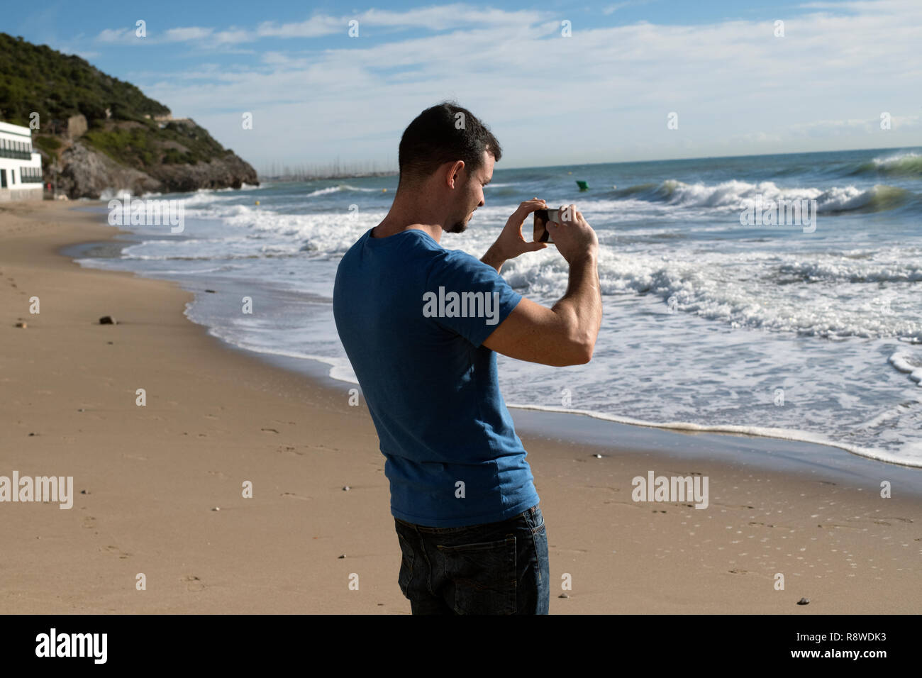 Young man taking photo of Mediterranean from beach in Garaff Spain Stock Photo
