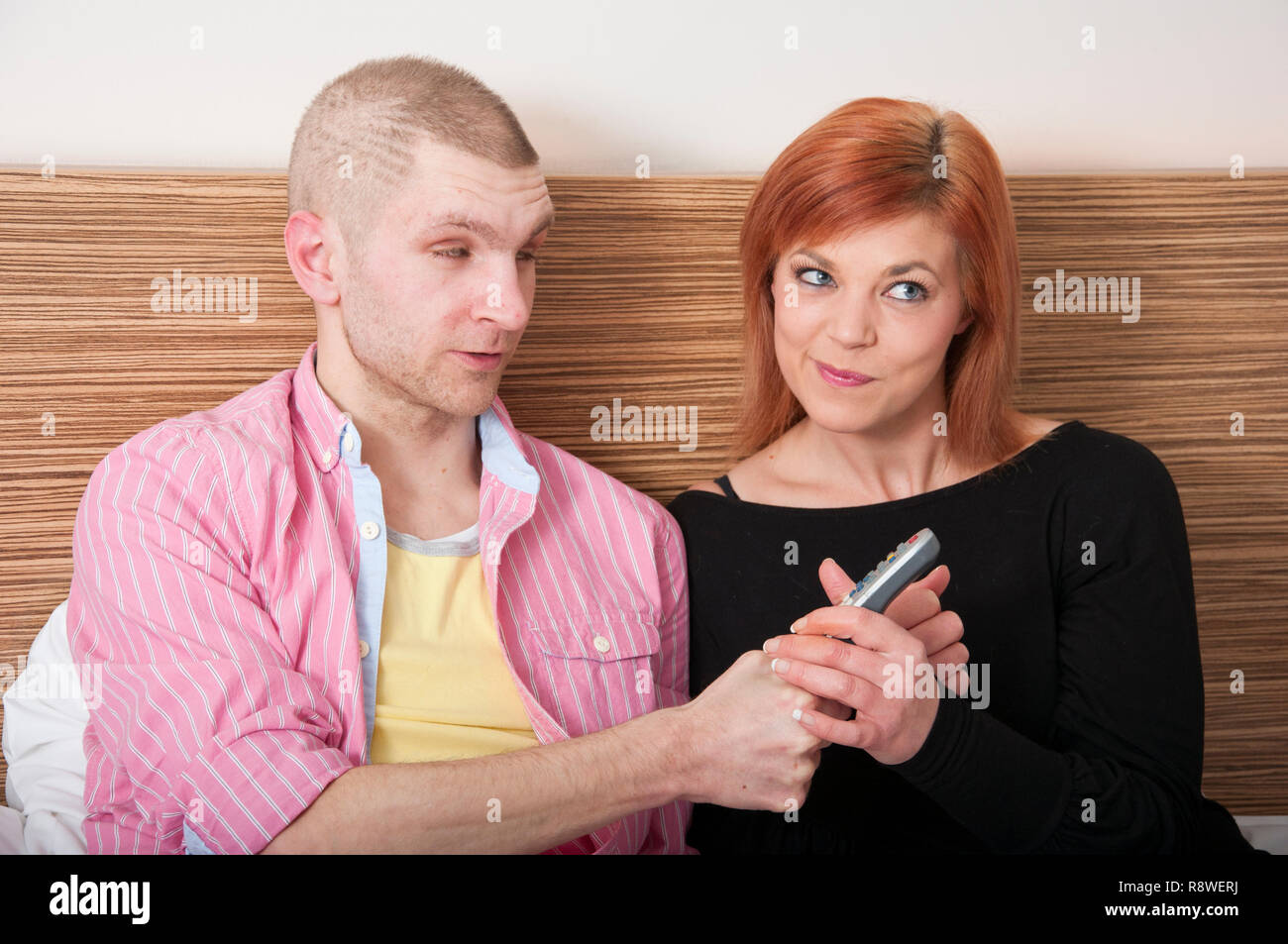 Young couple arguing fighting over TV remote control. Stock Photo