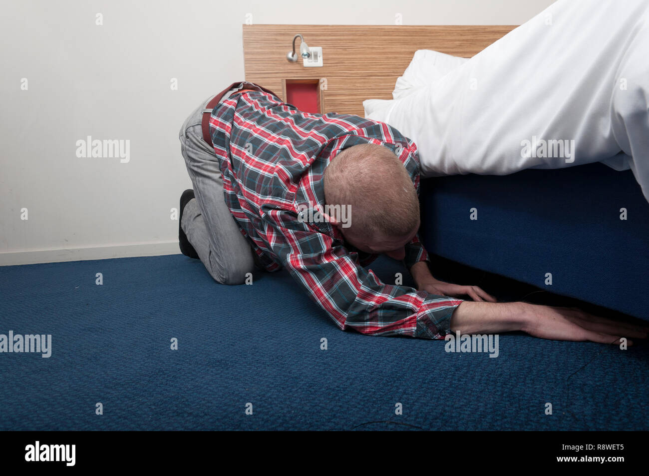 Man searching looking under bed Stock Photo Alamy