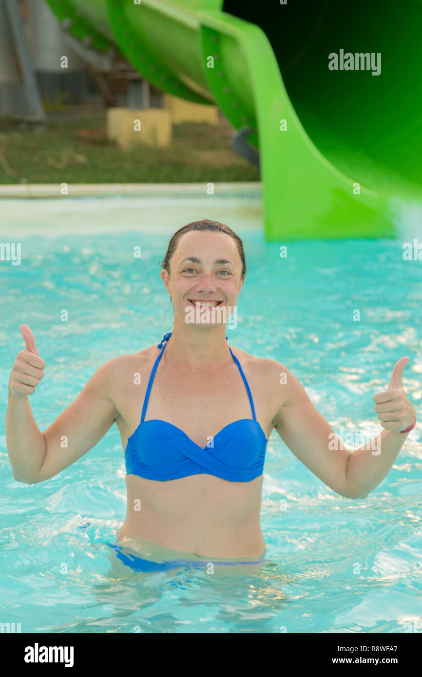 Happy girl in bikini sliding water park. Woman in a blue swimsuit. vertical  photo Stock Photo - Alamy