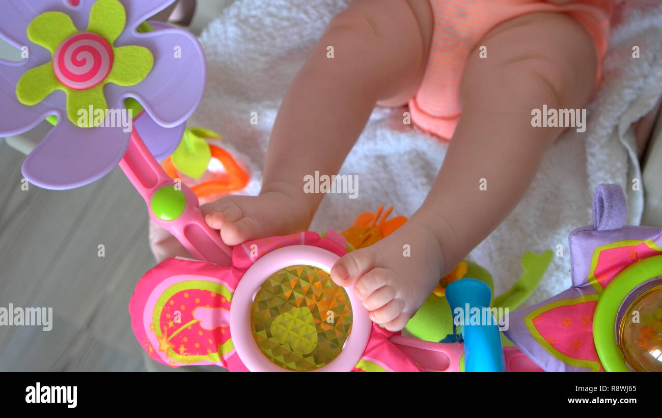 Newborn baby legs in crib with toys. Motor development of newborn kids ...