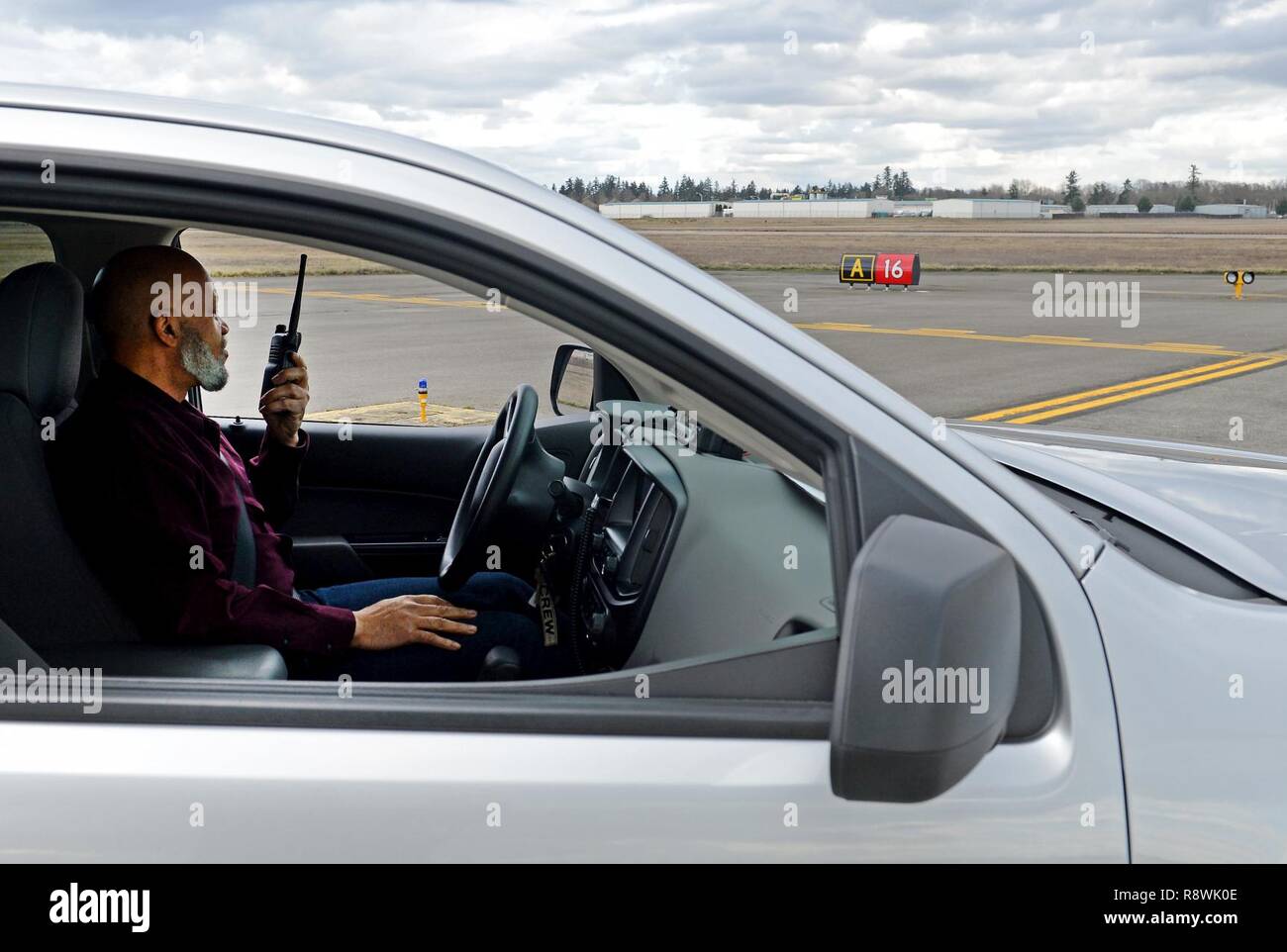 To avoid a runway incursion, Mr. Urouse Williams, 62nd Airlift Wing airfield driving program manager, demonstrates the proper way of contacting the air traffic control tower for clearance to drive on the McChord airfield Feb. 28, 2017 at Joint Base Lewis-McChord, Wash. A runway incursion is any unauthorized presence of an aircraft, vehicle or person on the safety protected area of a surface designated for the landing and take-off of aircraft. Stock Photo