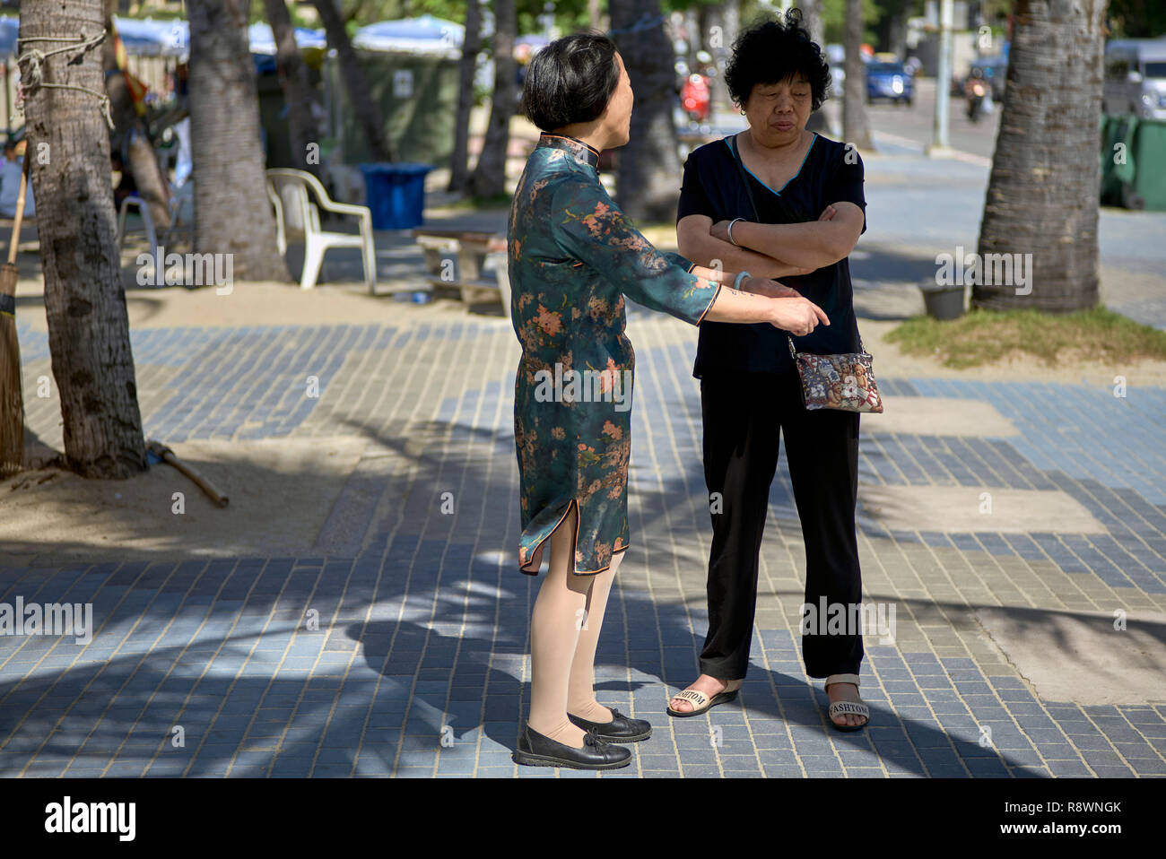 Chinese woman in traditional dress talking to Chinese female in Western clothes. Concept of old v new Stock Photo