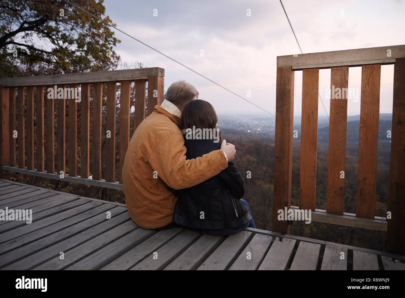 two young people couple, hugging together while sitting on deck ...