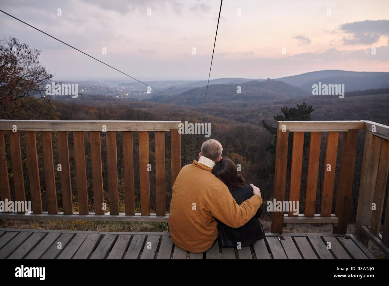 two young people couple, hugging together, sitting on deck, looking at ...