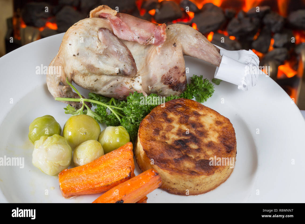Whole Quail wrapped in Bacon and oven roasted, served with Fondant potato and vegetables. Stock Photo