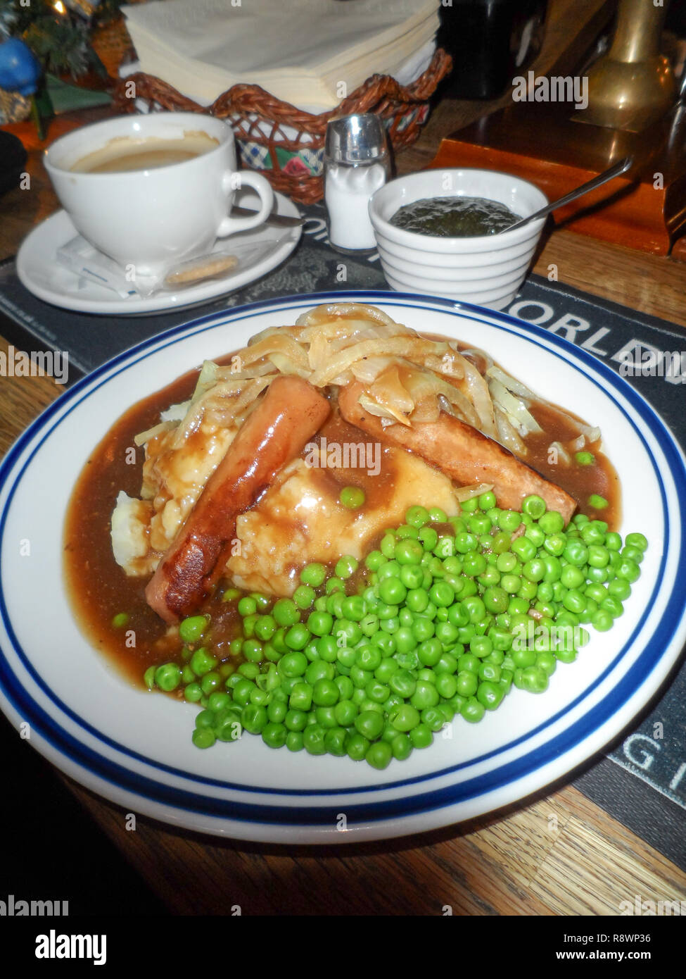Traditional sausage and mash served with onion gravy and peas in an