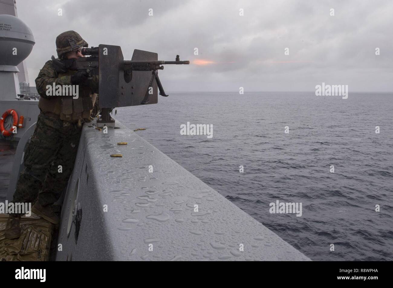 WATERS SOUTH OF JAPAN (March 11, 2017) Lance Cpl. Nathan Colter, assigned to the Battalion Landing Team, 2nd Battalion, 5th Marines, fires an M240B machine gun on the bridge wing of the amphibious transport dock ship USS Green Bay (LPD 20) during a defense of the amphibious task force exercise. Green Bay, part of the Bonhomme Richard Expeditionary Strike Group, with embarked 31st Marine Expeditionary Unit, is on a routine patrol, operating in the Indo-Asia-Pacific region to enhance warfighting readiness and posture forward as a ready-response force for any type of contingency. Stock Photo