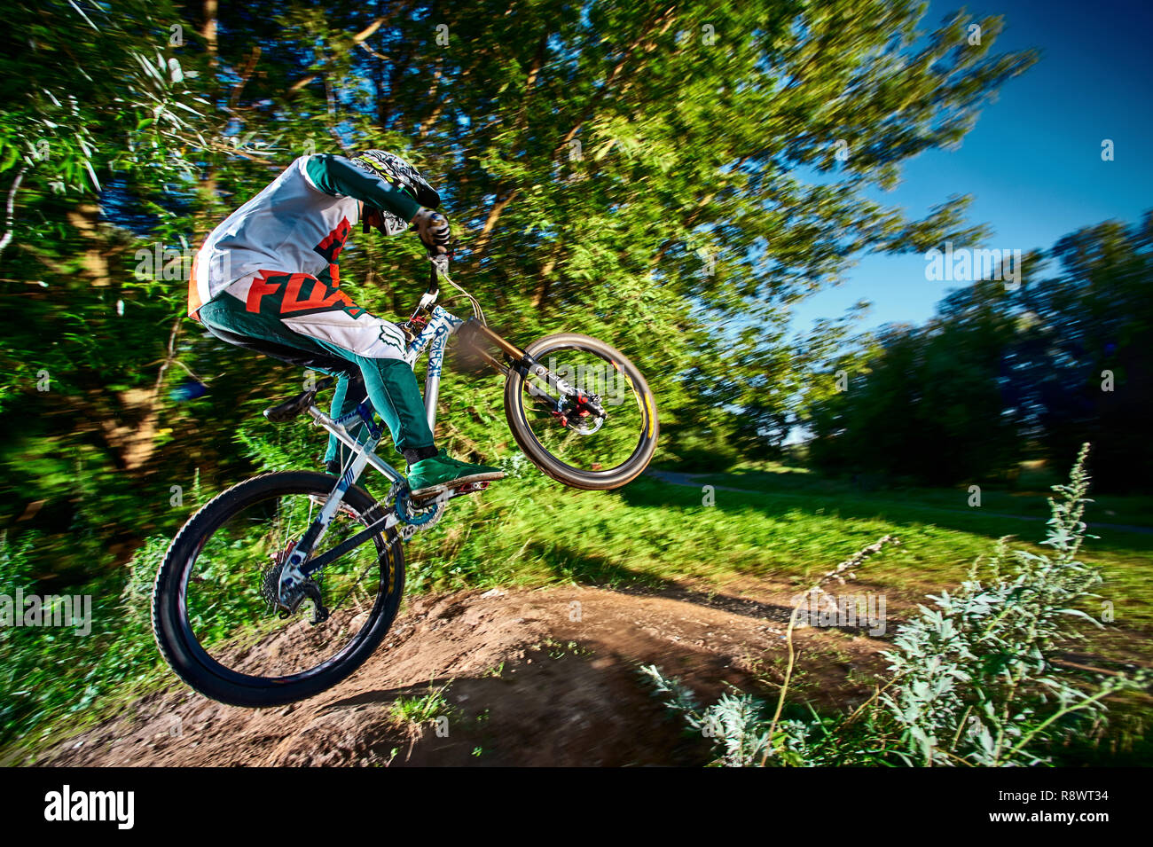 Moscow, Russia - August 31, 2017: Jump and fly on a mountain bike. Rider in action at mountain bike sport. Biker riding in forest. Cool athlete cyclis Stock Photo