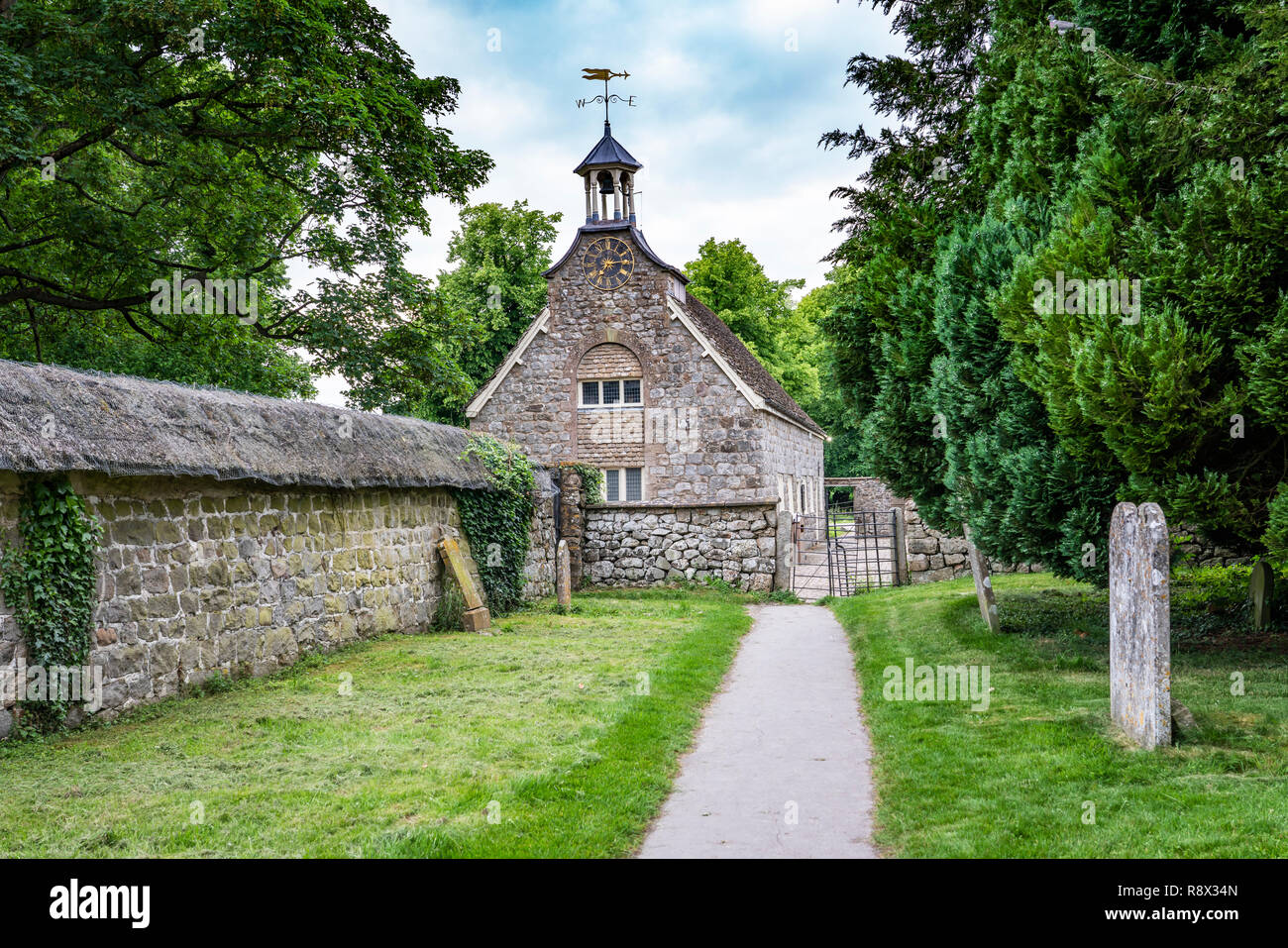An historic stone church and thatched wall in the village of Avebury, Wiltshire, England, Europe. Stock Photo