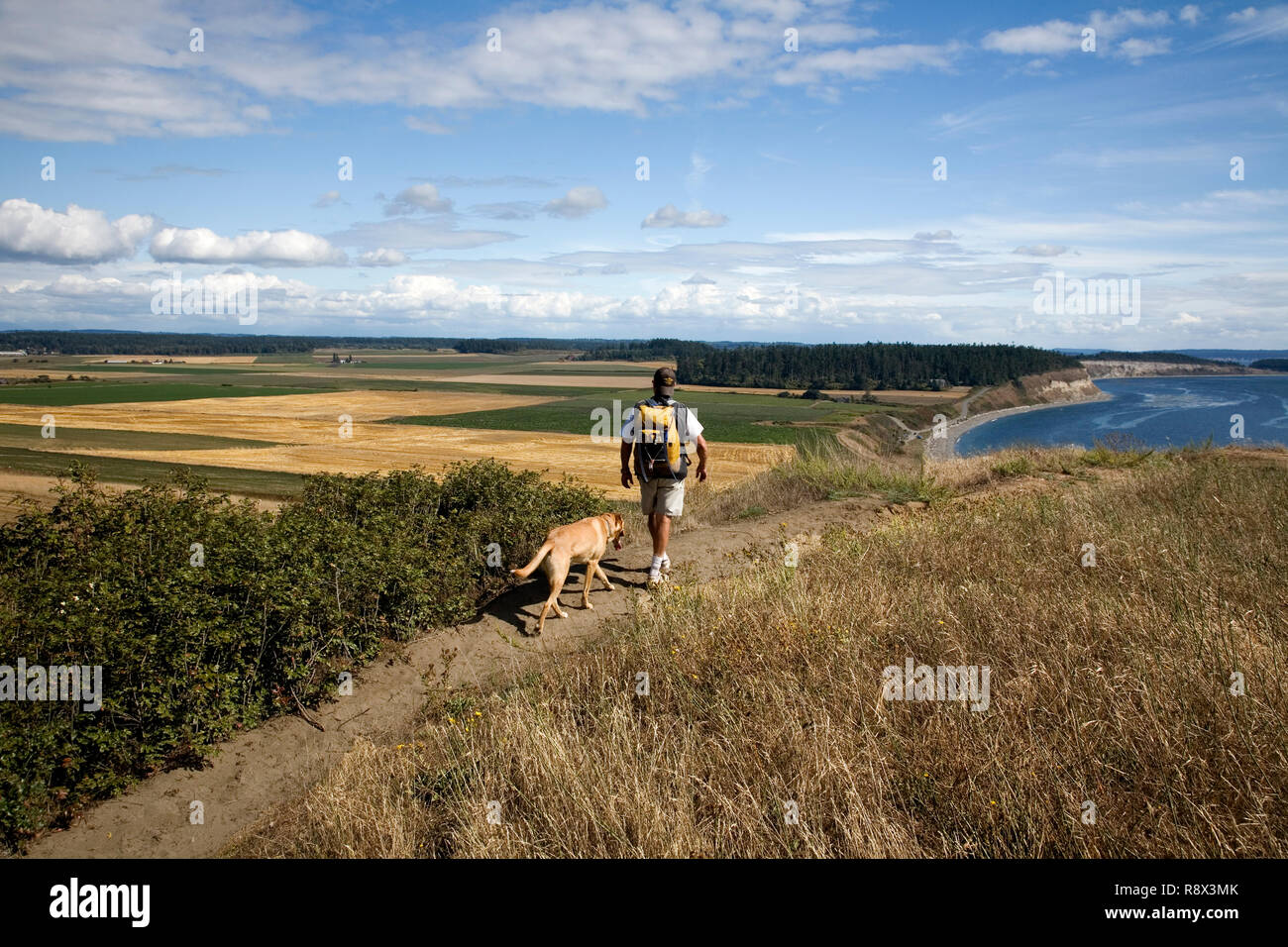 WA03558-00....WASHINGTON - Hiker with a dog on the Perego's Bluff Trail part of Nature Conservancy Land along the Strait of Juan de Fuca. Stock Photo