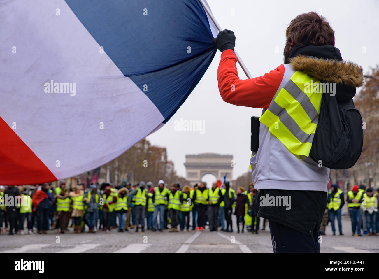 Yellow Vests demonstration (Gilets Jaunes) protesters against fuel tax, government, and President Macron with flag at Champs-Élysées, Paris, France Stock Photo