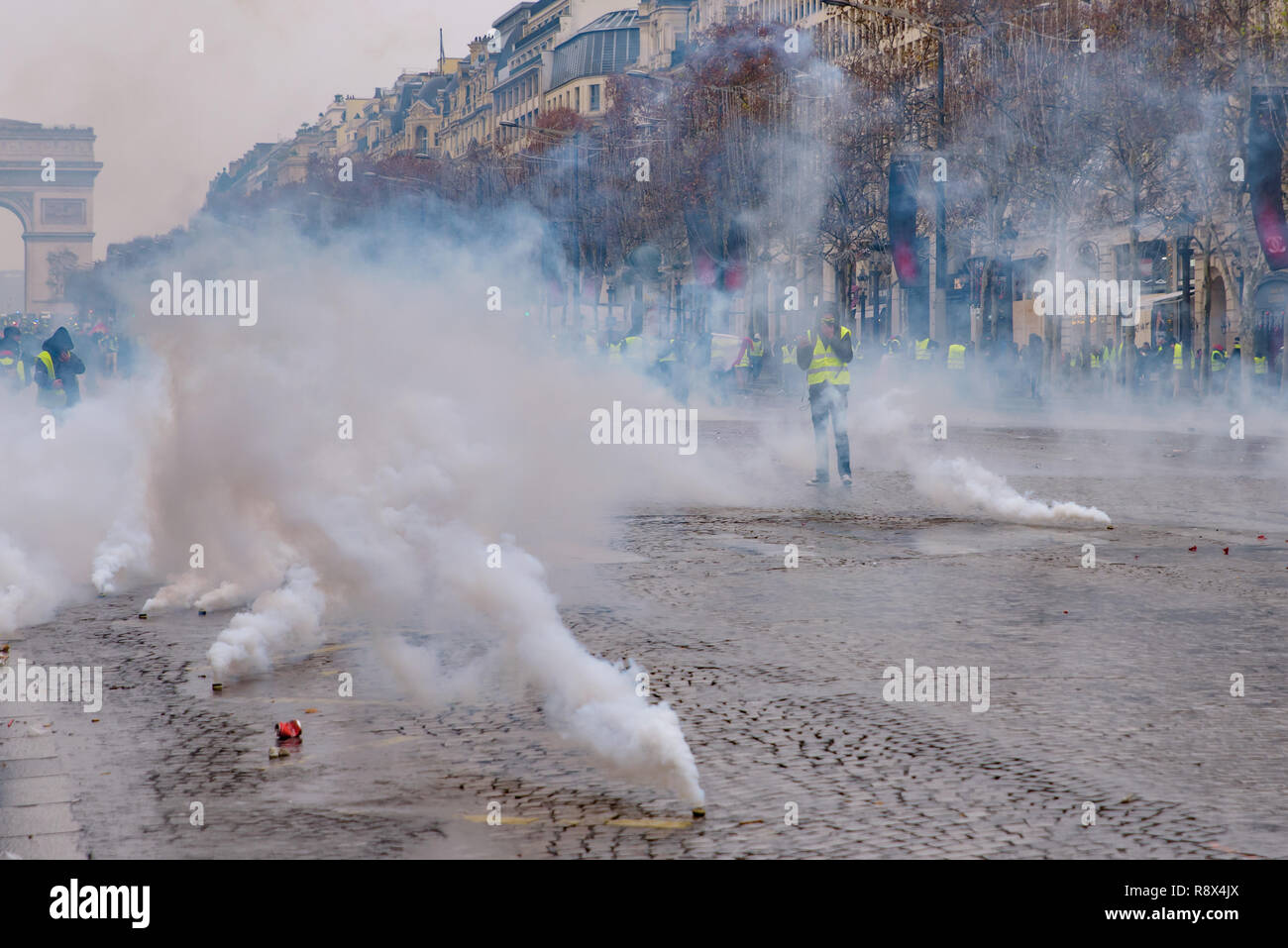 Riot police firing tear gas at Yellow Vests demonstration (Gilets Jaunes) protesters against government and French President at Champs-Élysées Stock Photo