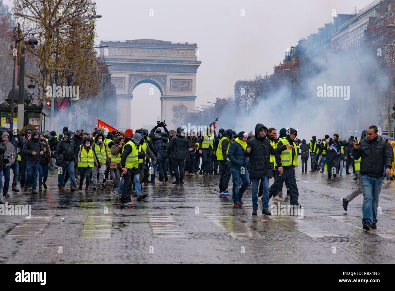 Riot police firing tear gas at Yellow Vests demonstration (Gilets Jaunes) protesters against government and French President at Champs-Élysées Stock Photo