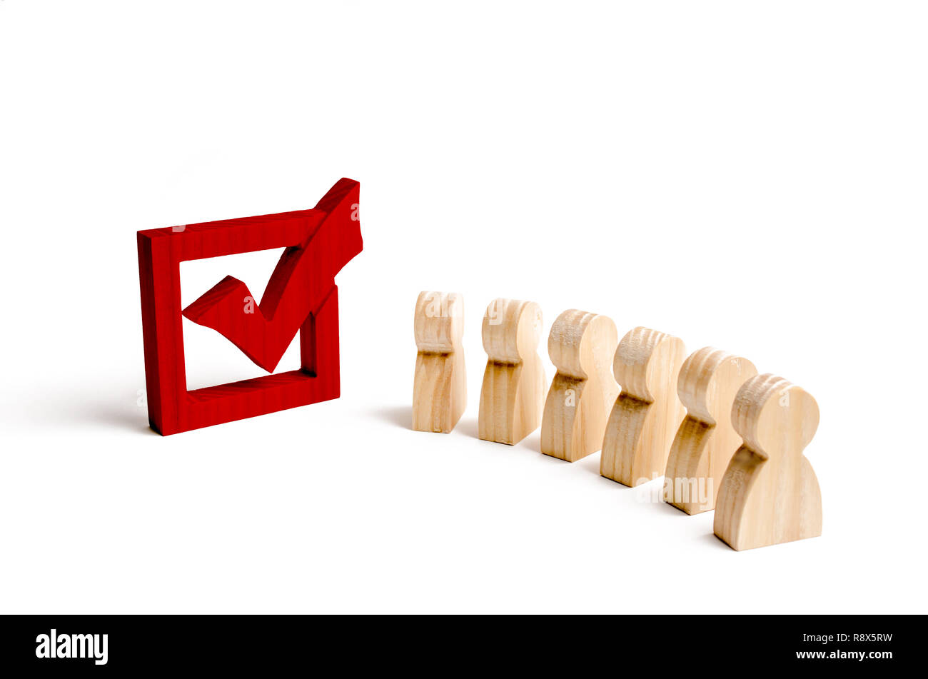 wooden human figures stand together next to a red tick in the box. The concept of elections and social technologies. Volunteers, parties, candidates,  Stock Photo