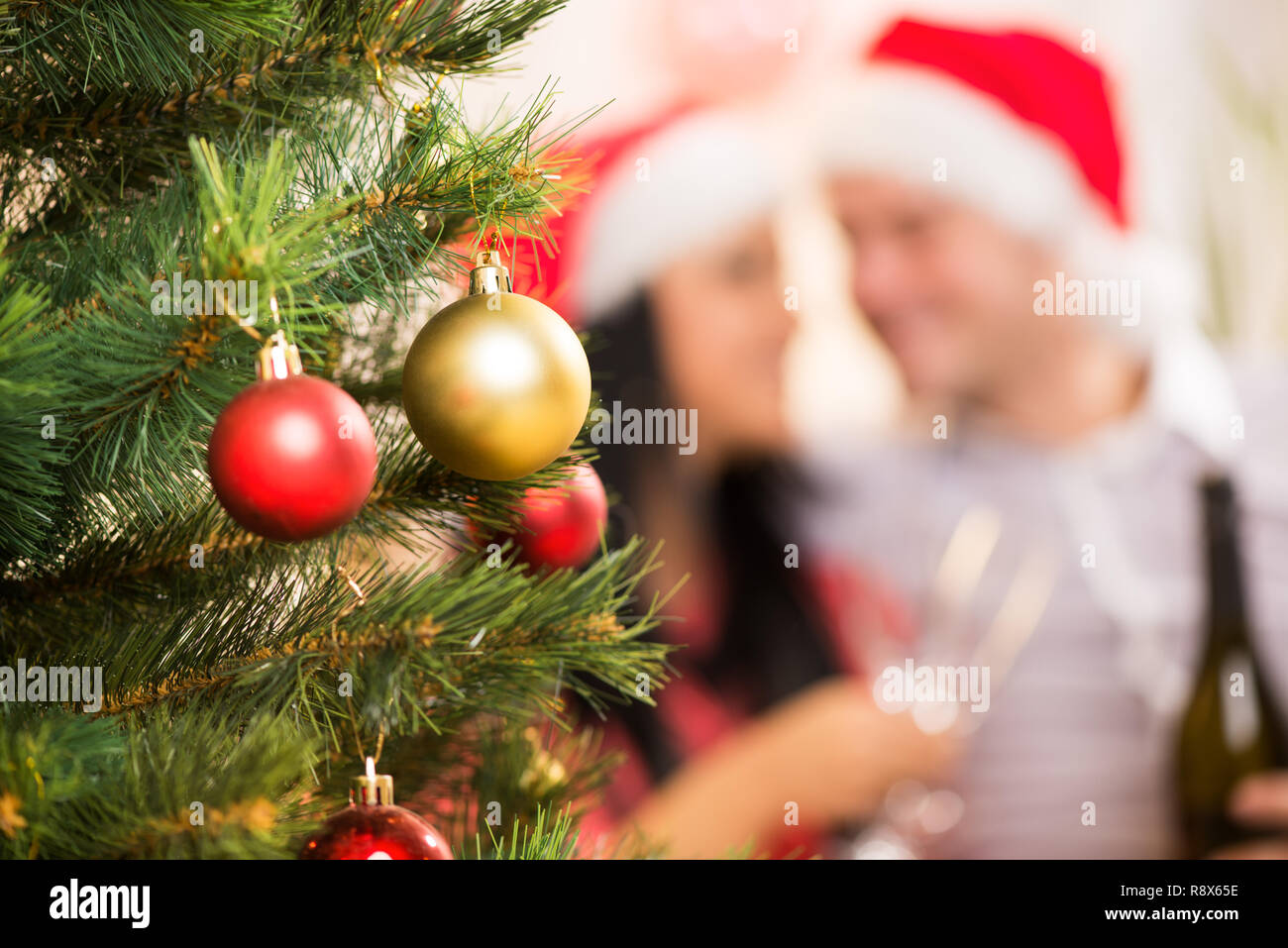 Christmas Tree with Christmas Decoration. Focus On Foreground. Background is Happy Christmas couple. Stock Photo