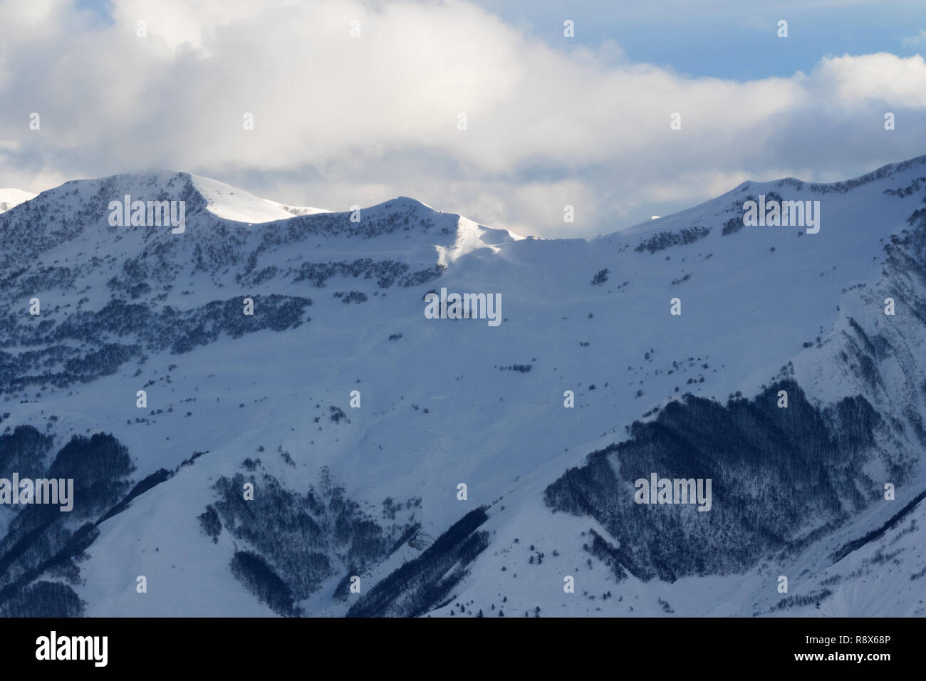 Snowy slope for freeriding and sunlight mountains in clouds at winter ...