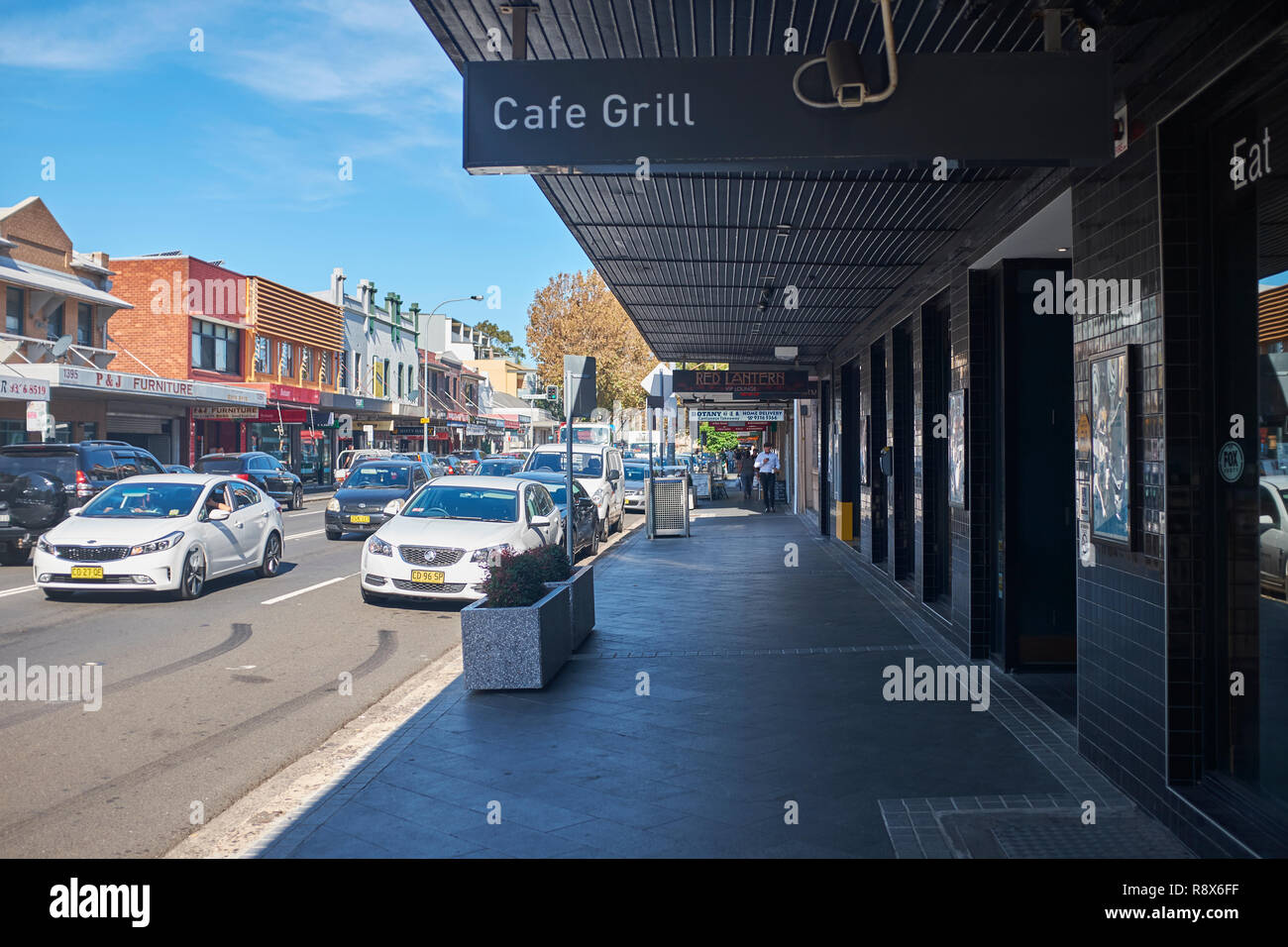 View of the high street in Botany from the pavement with shops and cars travelling through the town, Botany, Australia Stock Photo
