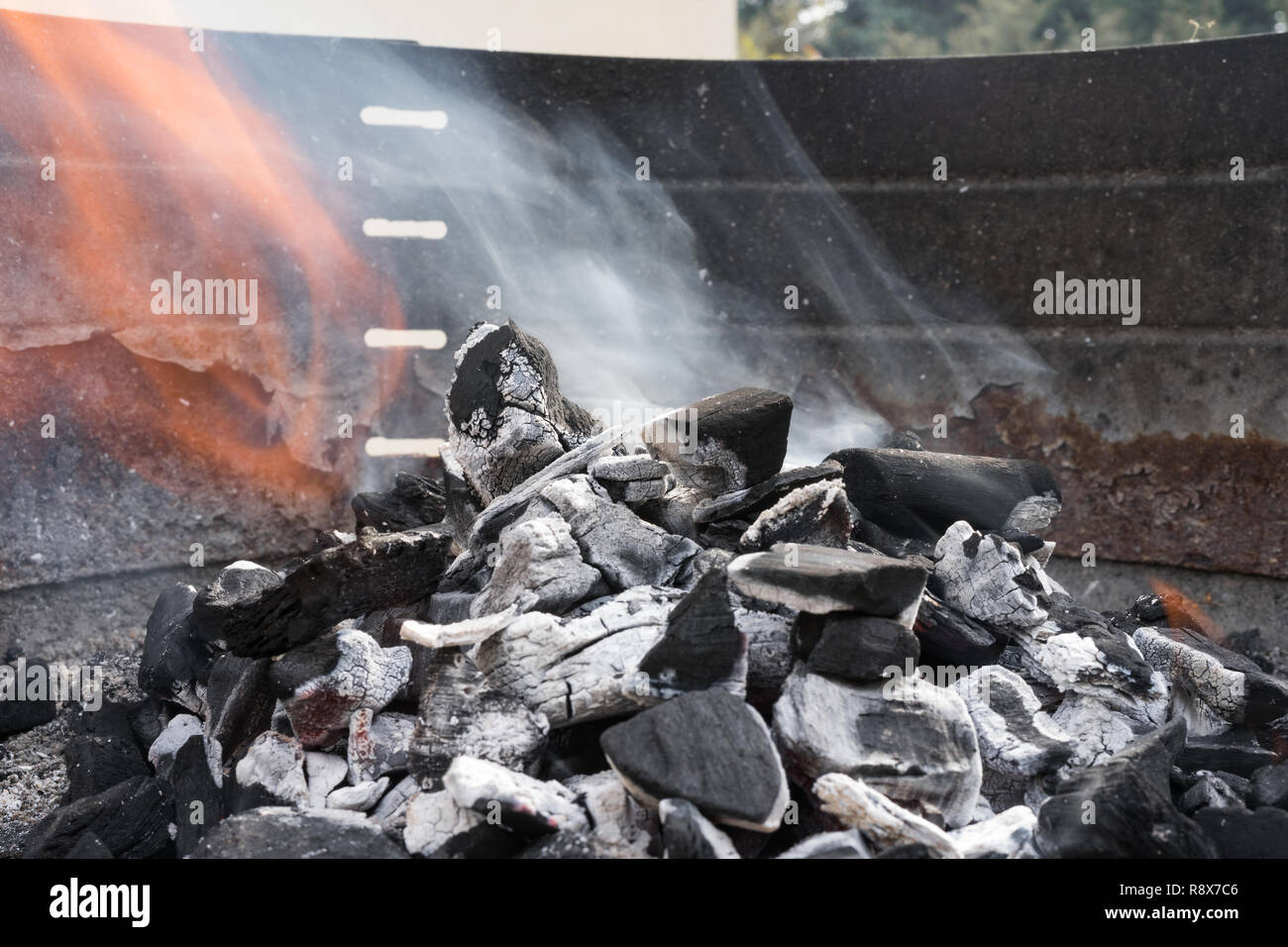 Black charcoal burning with smoke and fire in a barbecue grill