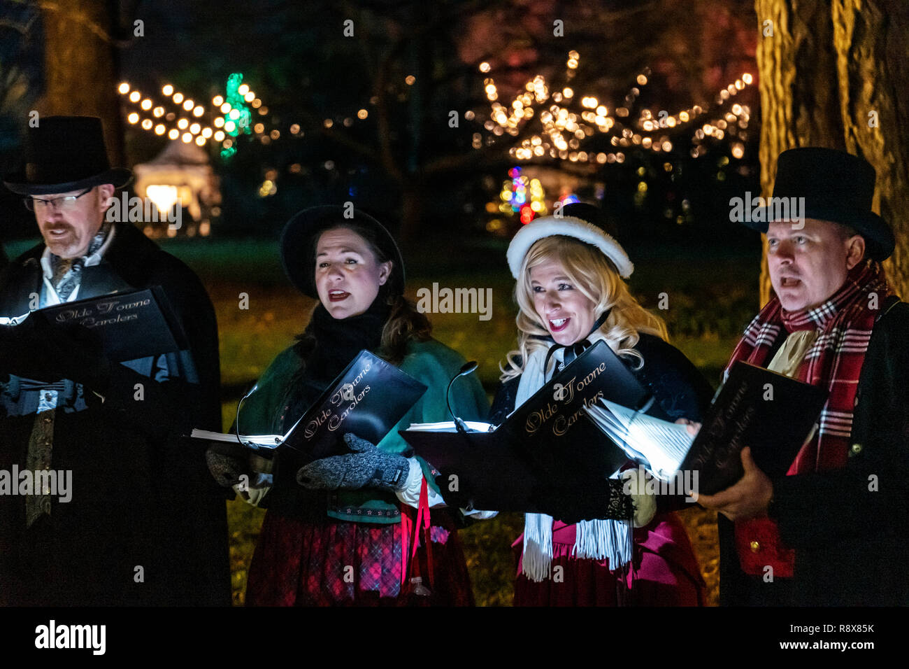 Carolers singing; night view of Christmas lights & decorations