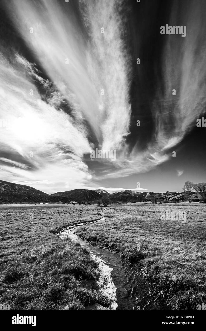 Black & white view; ranch pasture irrigation ditch; dramatic sky; Rocky Mountains; outside small town of Salida; Colorado; USA Stock Photo