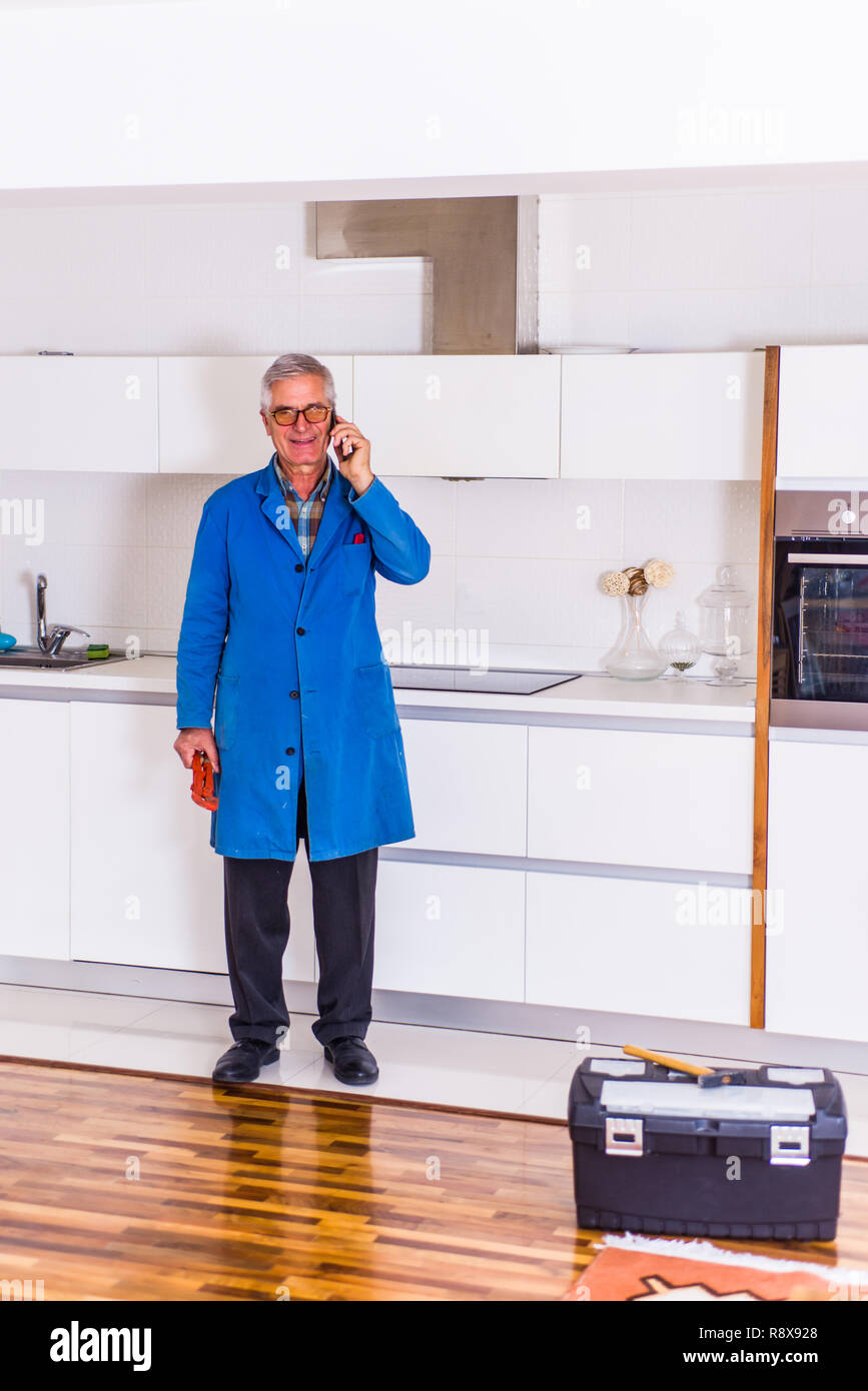 Workman standing in the kitchen, smiling and talking on mobile Stock Photo