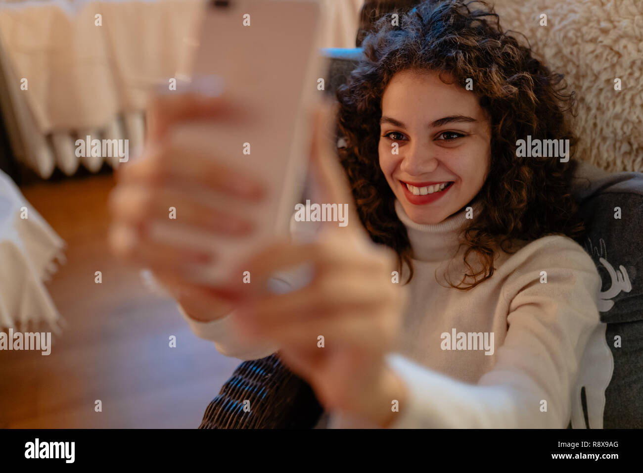 Smiling beautiful young woman with curly hair is taking a self-portrait Stock Photo