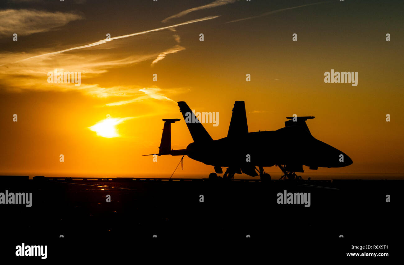 181202-N-LX838-0098 ATLANTIC OCEAN (Dec. 2, 2018) The sun sets behind an F/A-18C Super Hornet on the flight deck aboard the aircraft carrier USS George H.W. Bush (CVN 77). GHWB is underway in the Atlantic Ocean conducting routine training exercises to maintain carrier readiness. (U.S. Navy photo by Mass Communication Specialist Seaman Steven Edgar) Stock Photo