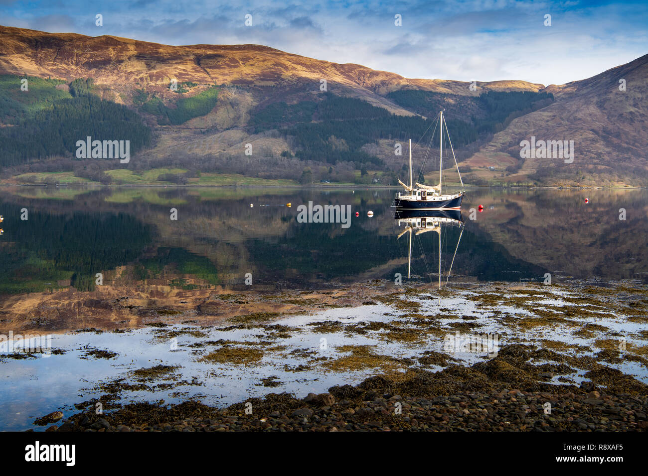 Blue sailboat reflected in the waters of Loch Leven, Scotland. Stock Photo