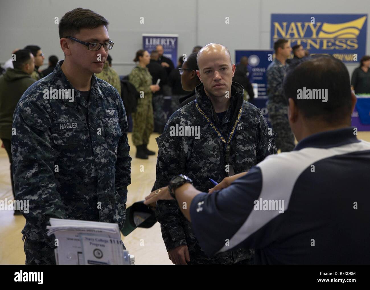 NEWPORT NEWS, Va. (Dec. 6, 2018) Aviation Electrician's Mate 1st Class Christopher Hagler, from San Luis Obispo, California, left, and Aviation Electronics Technician 2nd Class Brandon Walker, from Woodbridge, Virginia, assigned to USS Gerald R. Ford's (CVN 78) aircraft intermediate maintenance department, meet with a college representative during the 2018 Newport News College Fair. Ford and USS George Washington (CVN 73) organized the event in which more than dozen colleges met with Sailors to discuss higher education opportunities. U.S. Navy Stock Photo