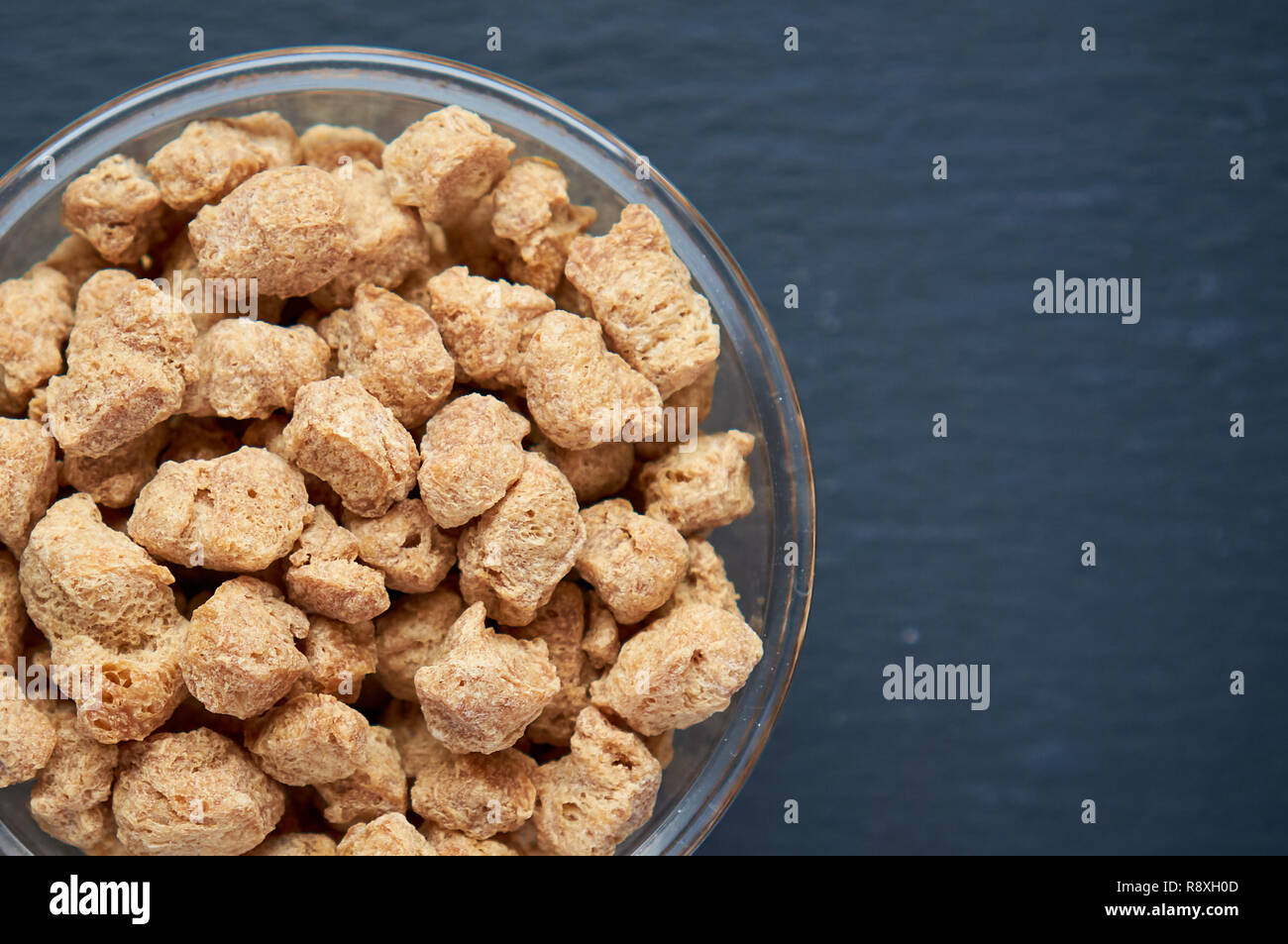 Healthy, nutritious soybean meat, chunks in a white bowl. Top view of raw soya chunks in bowl on dark background. Stock Photo