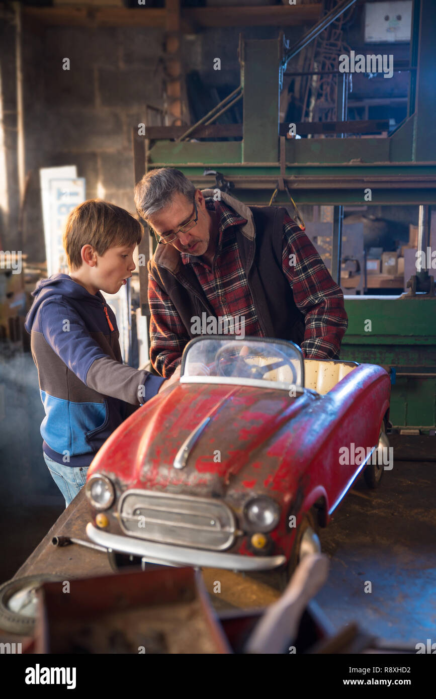 Father And His Young Son In A Diy Workshop To Repair A Pedal Car Stock Photo Alamy