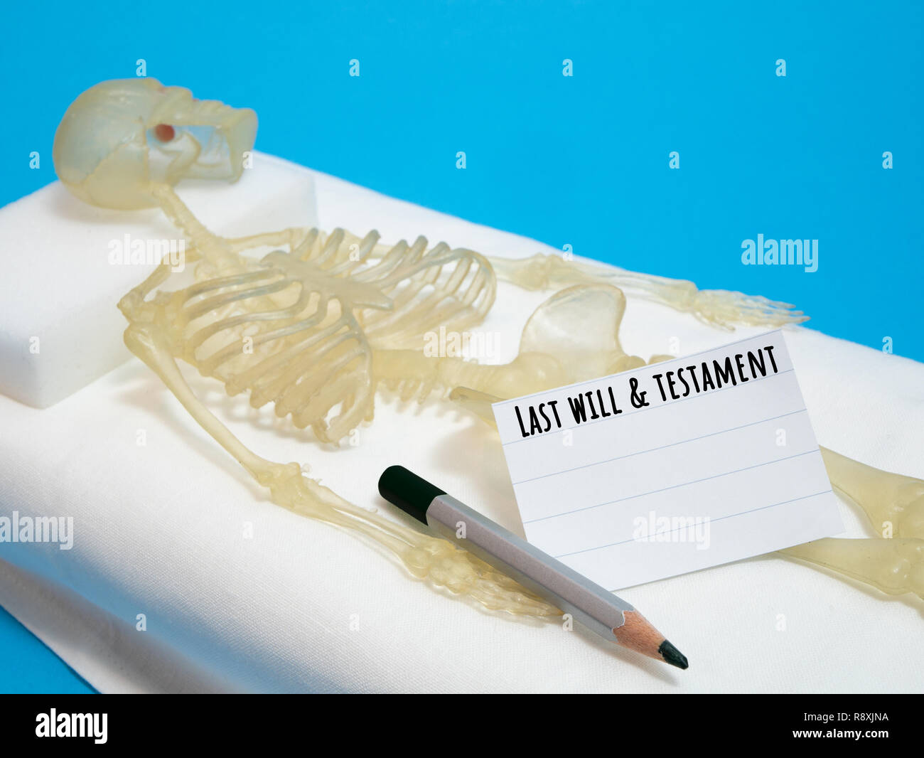 last will and testament concept with human skeleton laying on deathbed with pencil and piece of paper Stock Photo