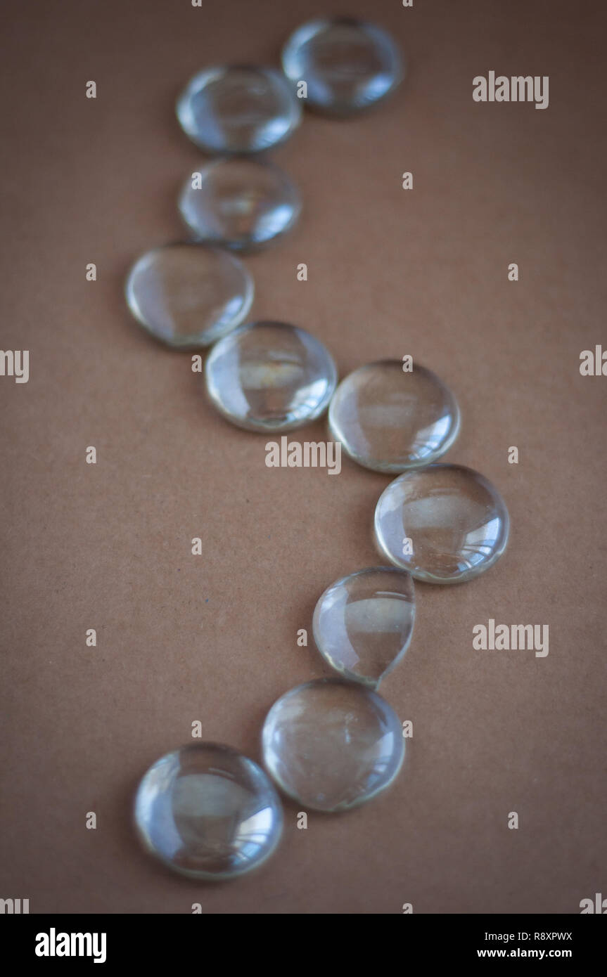Clear marbles with light reflections on a brown background. Stock Photo
