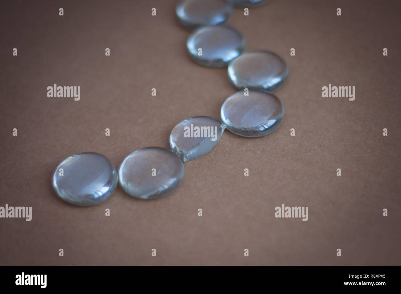 Clear marbles with light reflections on a brown background. Stock Photo