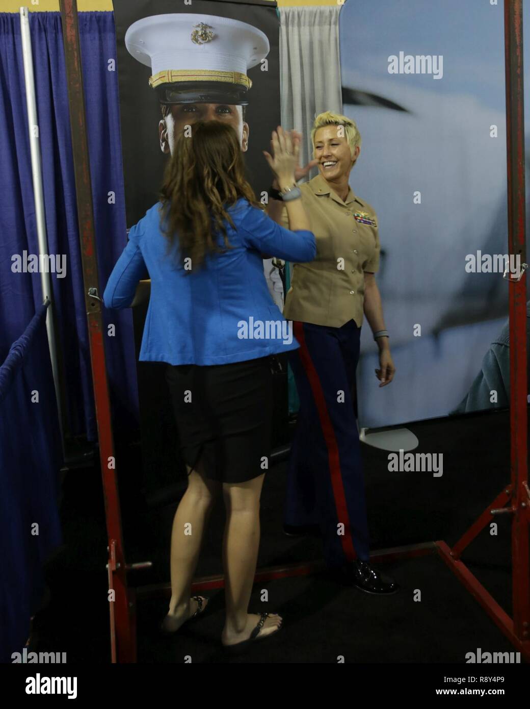 Major Carrie Compton, a C-130 pilot from Forth Worth, Texas, "high-five's"  an attendee of the 2017 Women in Aviation International Symposium as she  completes a set of pull-ups. The United States Marine