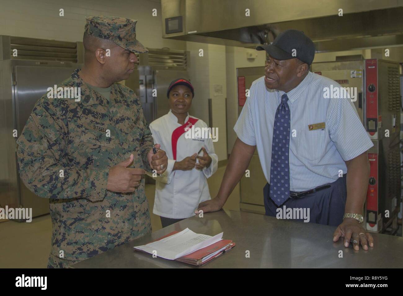 U.S. Marine Corps Master Gunnery Sgt. Derreck Steele, left, staff non-commissioned officer in charge, food service school, Fort Lee, consults with the staff to evaluate how the program is run at the 31 area mess hall on Camp Pendleton, Calif., March 7, 2017. The William Pendleton Thomas Hill competition is held to judge the best mess hall in the Marine Corps. Stock Photo