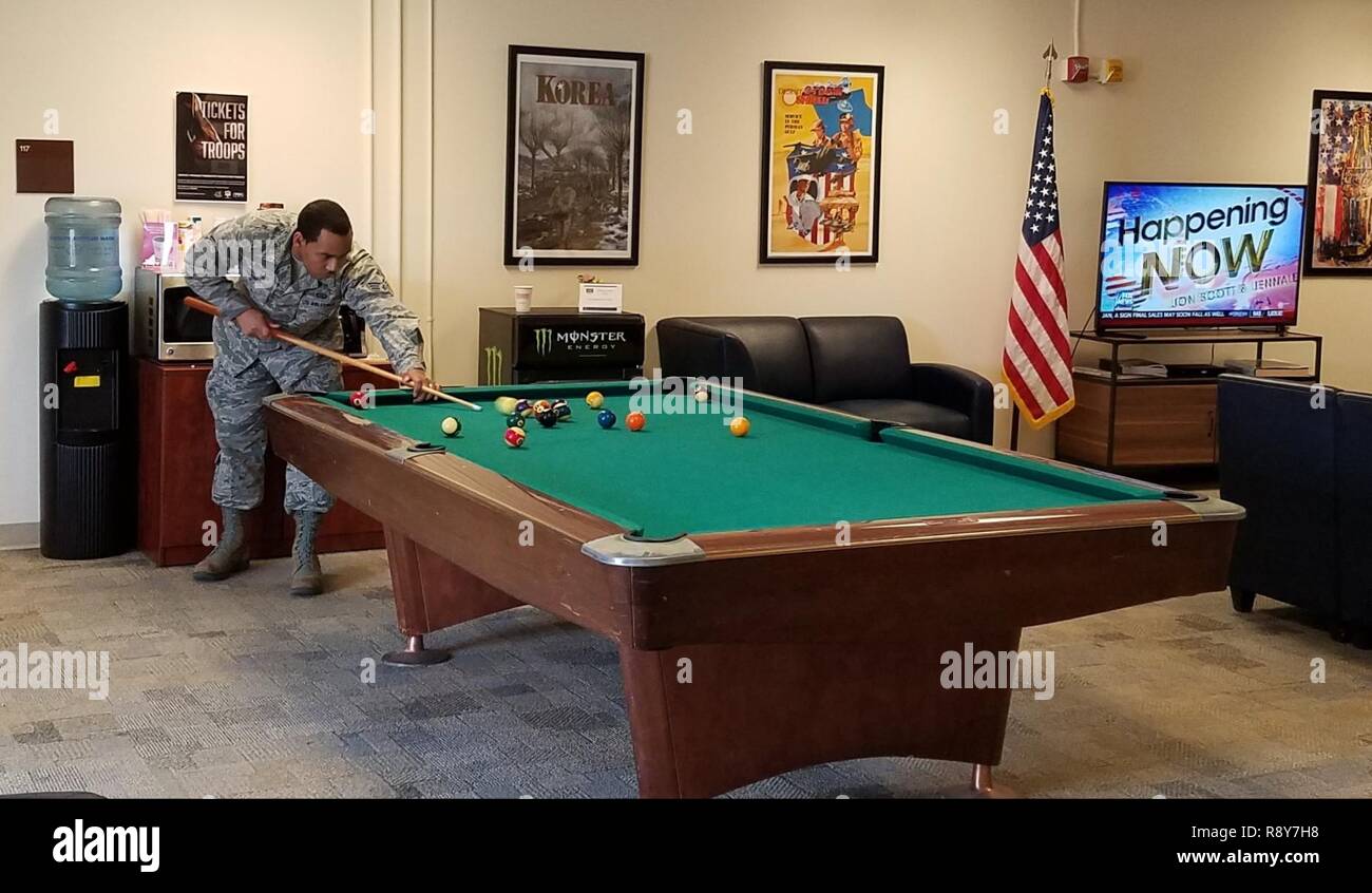 U. S. Air Force Senior Airman Anthony Tucker, Airman Leadership School student, plays pool at the USO’s multipurpose activity room at Joint Base Langley-Eustis, Va., Feb. 28, 2017. The Langley Air Force Base USO center, located in the Professional Development Center, provides a lounge area for ALS students and offers free snacks, coffee, books, cable television, video games, computer access, Wi-Fi and printers for service members and their families. Stock Photo