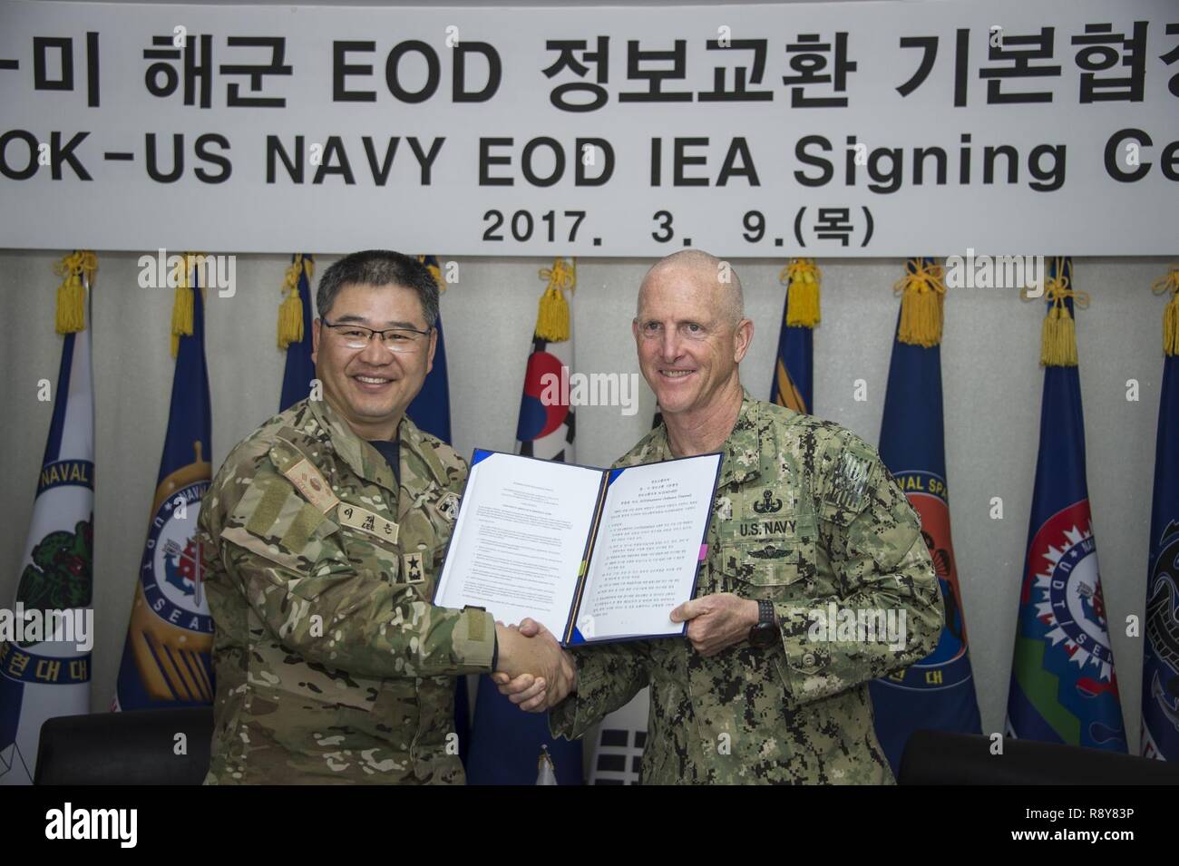 Commander, Republic of Korea (ROK) Naval Special Warfare Flotilla, Rear Adm. Jae Eun Lee, and Commander, Task Force 75, U.S. Navy Capt. Robert A. Baughman, shake hands after signing an information exchange agreement in Jinhae, ROK, March 9, 2017, as part of exercise Foal Eagle 2017. The agreement addresses research and development practices between the two nations, promotes explosive ordnance disposal interoperability, and enhances future readiness. Stock Photo
