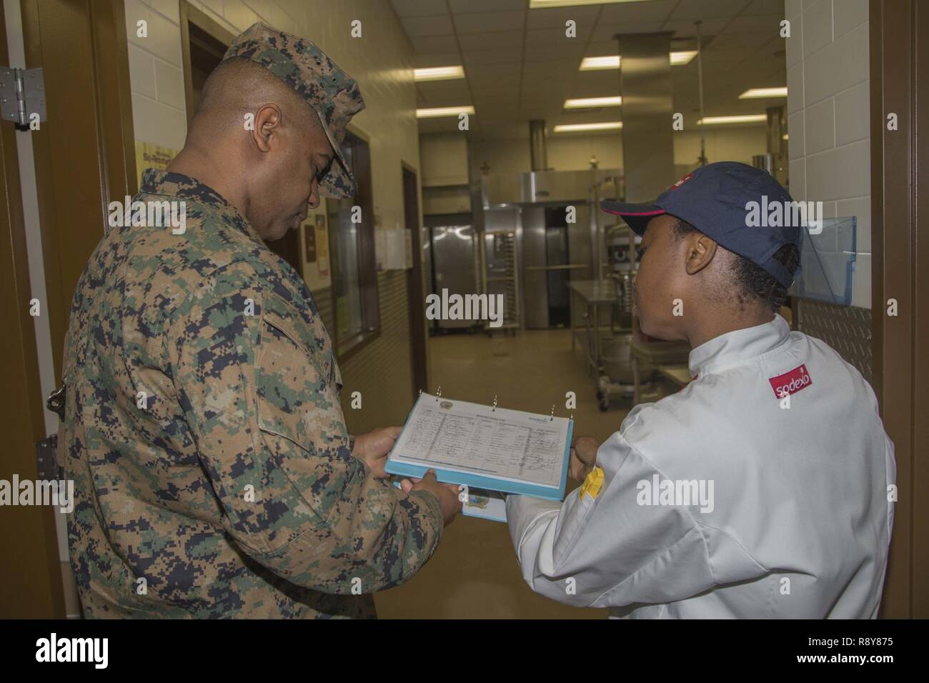 U.S. Marine Corps Master Gunnery Sgt. Derreck Steele, left, staff non-commissioned officer in charge, food service school, Fort Lee, consults with Natalie Williams, production manager, to evaluate how the program is run at the 31 area mess hall on Camp Pendleton, Calif., March 7, 2017. The William Pendleton Thomas Hill competition is held to judge the best mess hall in the Marine Corps. Stock Photo