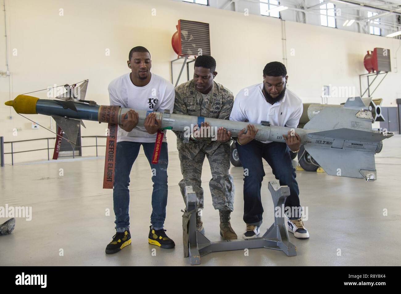 Malcolm Mitchell, left, New England Patriots’ wide receiver and Super Bowl LI Champion, Capt. Eric Johnson 23d Civil Engineer Squadron commander and James Rome, former NFL tight end lift an AIM 9 Sidewinder II missile during Mitchell’s visit March 7, 2017, at Moody Air Force Base, Ga. Mitchell, who is a Valdosta native, got a glimpse of a typical day in the life of some of Moody’s Airmen from the 23d Fighter Group, 23d Maintenance Group, 23d Mission Support Group, and the 820th Base Defense Group. During his visit, Mitchell also spent time with Airmen and signed autographs for local Patriots f Stock Photo