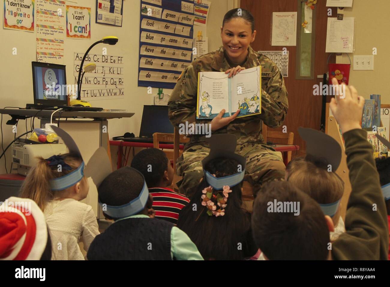 Pfc. Elise M. Fuentes, a military police with 218th Military Police Company, 716th MP Battalion, 101st Airborne Division (Air Assault) Sustainment Brigade, 101st Abn. Div., shows first grade students the illustrations in a book, March 2, 2017, during Read Across America Day at Marshall Elementary School on Fort Campbell, Kentucky. Marshall Elementary School celebrated the 20th anniversary of Read Across America by inviting Soldiers from 716th MP Bn. to read to the elementary students and by putting together a production of Dr. Seuss’s “The Cat in the Hat.” Stock Photo