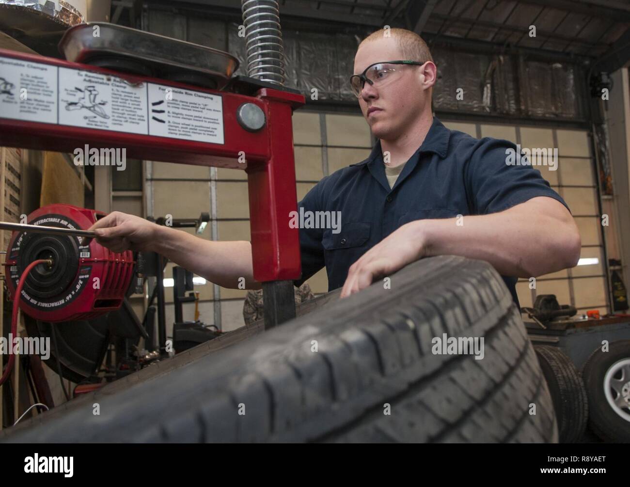 Senior Airman Nicholas Oukrop, 5th Logistics Readiness Squadron vehicle maintenance technician, replaces an old tire at Minot Air Force Base, N.D., Feb.28, 2017. The maintainers use a tire clamp machine to remove each tire from its rim while performing maintenance. Stock Photo