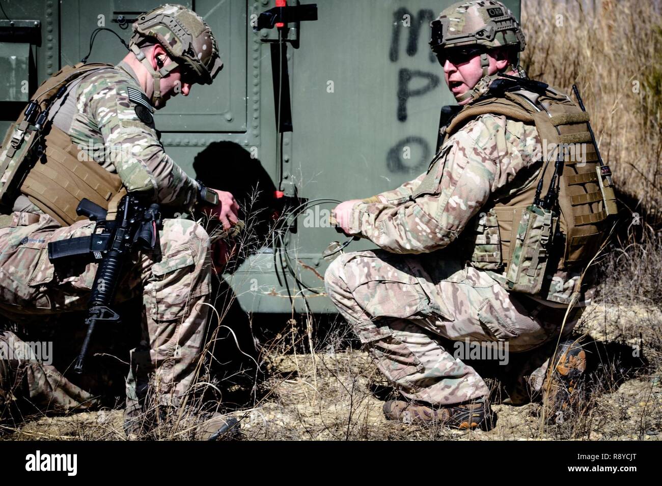 U.S. Air Force Explosive Ordinance Disposal Technicians start to plant charges to breach a door while Tactical Air Control Party Airmen set up security positions during an exercise at Warren Grove Gunnery Range, N.J., March 8, 2017. Stock Photo