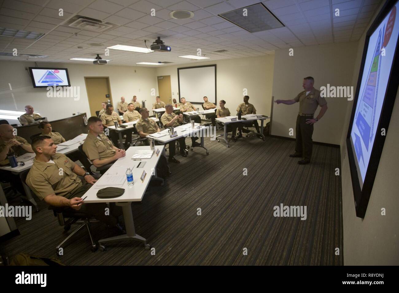 U.S. Marine Capt. Scott L. Campbell, maintenance officer with Marine Aviation Weapons and Tactics Squadron One (MAWTS-1) welcomes students attending the first ever Advanced Aircraft Maintenance Officer Course (AAMOC) at Marine Corps Air Station Yuma, Ariz., on Mar. 13, 2017. AAMOC will empower Aircraft Maintenance Officers with leadership tools, greater technical knowledge, and standardized practices through rigorous academics and hands on training in order to decrease ground related mishaps and increase sortie generation. Stock Photo