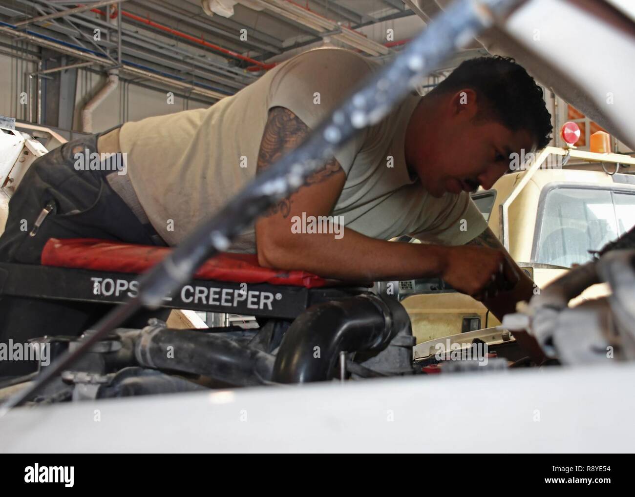 U.S. Air Force Senior Airman Cedric Castillo, a heavy maintenance shop mechanic with the 379th Expeditionary Logistics Readiness Squadron Vehicle Management Flight, works on the engine of a vehicle at Al Udeid Air Base, Qatar, March 13, 2017. When lease and government vehicles break down at Al Udeid, the Airmen of the vehicle management flight are the ones that troubleshoot and repair them. Stock Photo